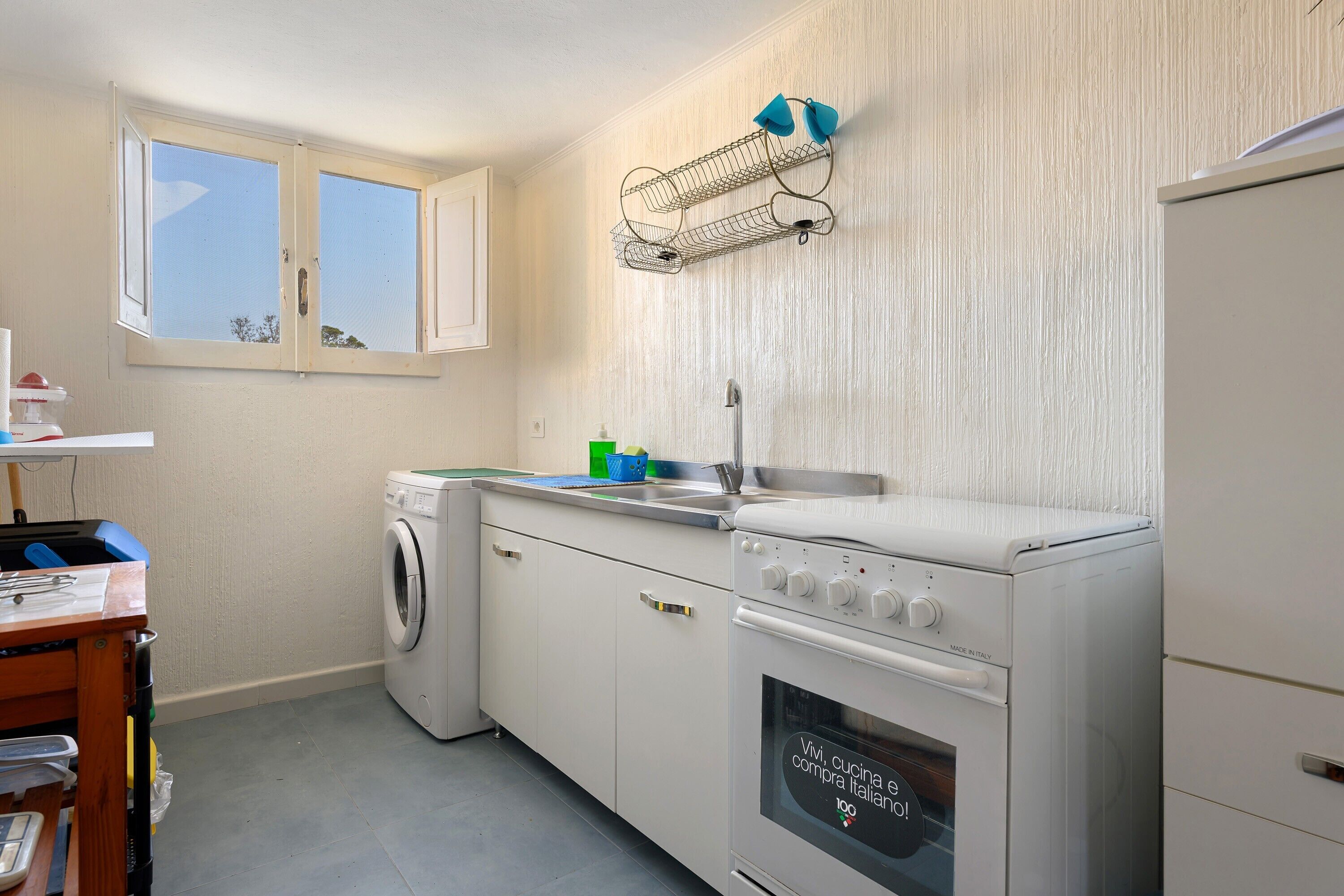 Une cuisine compacte équipée d’un lave-linge, d’un four encastré et d’une fenêtre offrant une vue agréable.