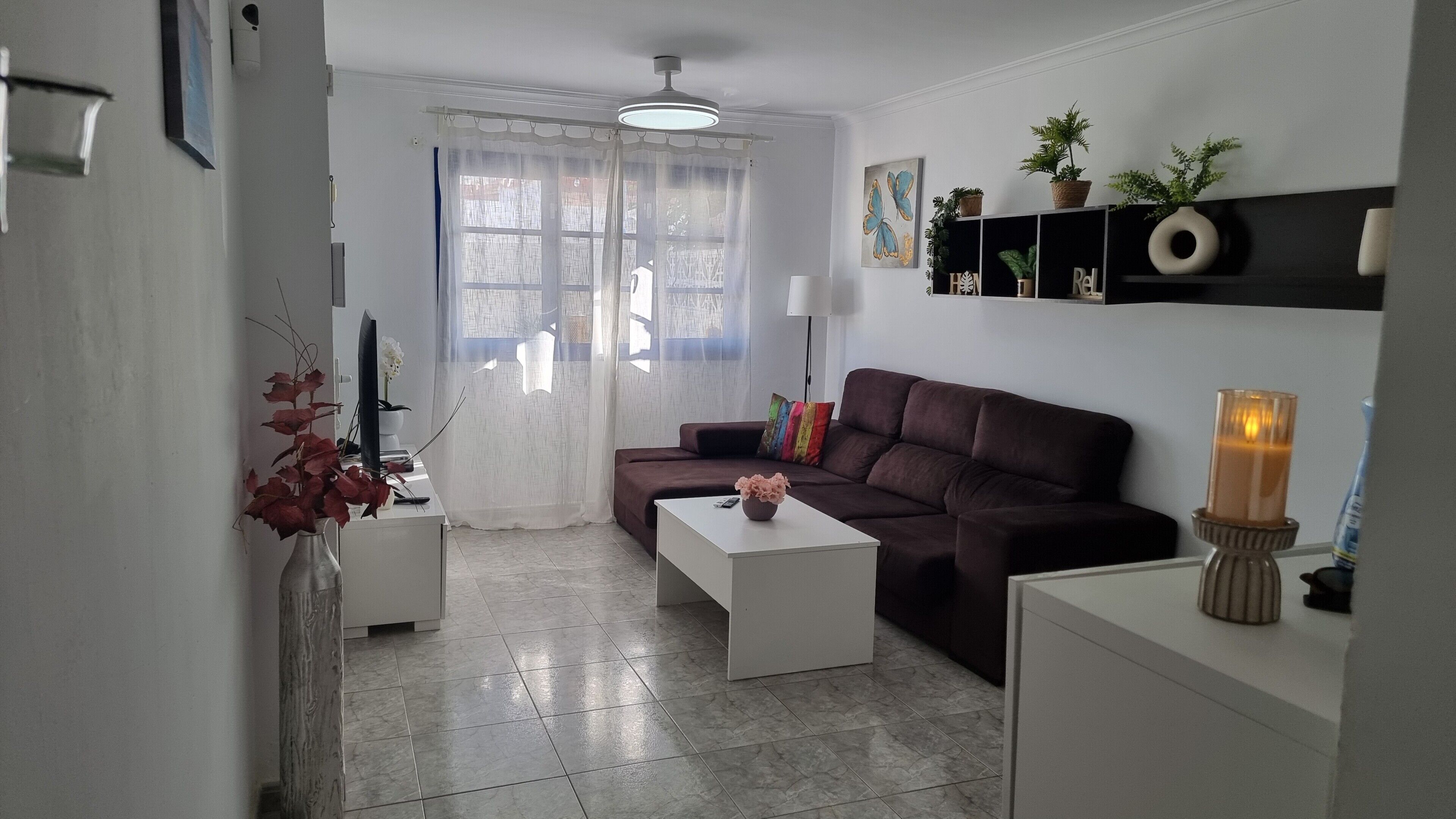 A living room with a sofa, coffee table, TV, and decorative items.