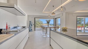 Een moderne keuken met een centraal eiland, een eetgedeelte met een tafel en stoelen, en uitzicht op de omgeving.