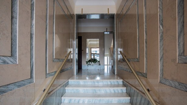 Un escalier en marbre, agrémenté de rampes dorées, mène à un palier.