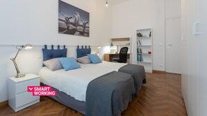 Une chambre moderne avec un grand lit, des tables de chevet, un bureau et une bibliothèque.