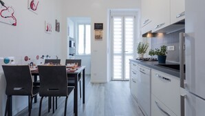 Une cuisine moderne avec des meubles blancs, un four encastré et un coin repas comprenant une table et des chaises.