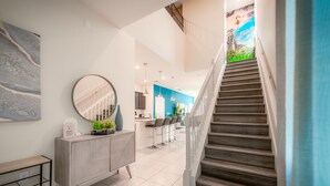 A modern interior with a staircase, a kitchen area, and a dining space. - Luxury 7 Bed w/Pool, Home Theater, & Themed Gameroom! (Davenport)
