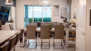 A modern dining area with a large table, four chairs, and a geometric chandelier. - Luxury 7 Bed w/Pool, Home Theater, & Themed Gameroom! (Davenport)