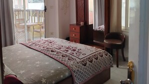 Une chambre à coucher avec un lit, une commode, une chaise, un miroir et une fenêtre.