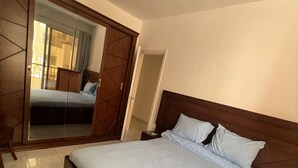 Un dormitorio con una cama grande, un armario con espejo y una mesita de noche.