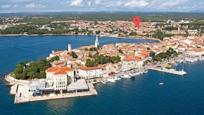 An aerial view of a coastal town with a marina, buildings with red-tiled roofs, and a prominent tower. - Apartment Parentium - Stay in the Heart of Porec (Porec)