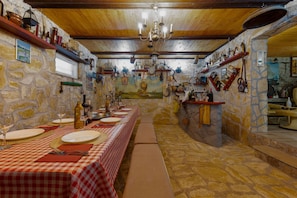 A long dining table with checkered tablecloths, surrounded by stone walls and wooden beams. - Villa Fenix (Benkovac)