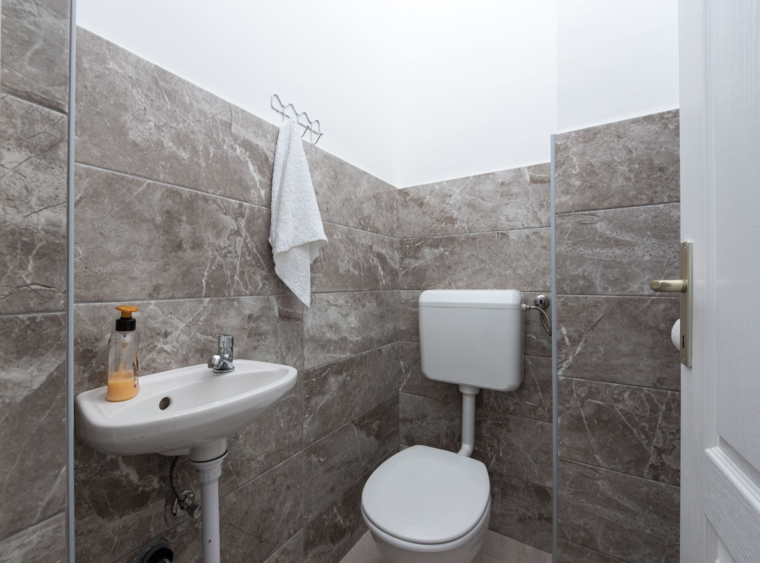 A bathroom with a white sink, toilet, and marble walls.