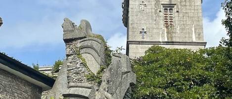 A stone tower with a cross on top, surrounded by greenery.