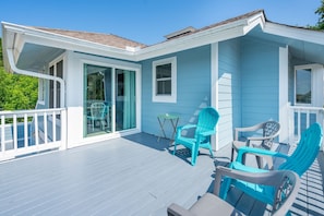 A blue house with a porch, a sliding glass door, and a small table with chairs.