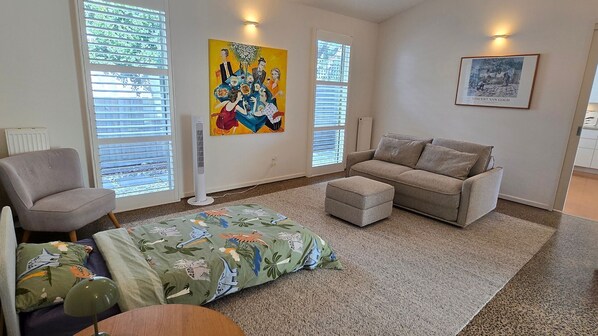A living room with a sofa, armchair, ottoman, and a colorful rug. - Marittimo - Point Lonsdale (Point Lonsdale)