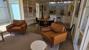 Un salon moderne avec des canapés en cuir, une table basse ronde et une bibliothèque remplie de livres.