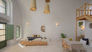 A spacious room with a wooden bench, a dining table with chairs, and a staircase.
