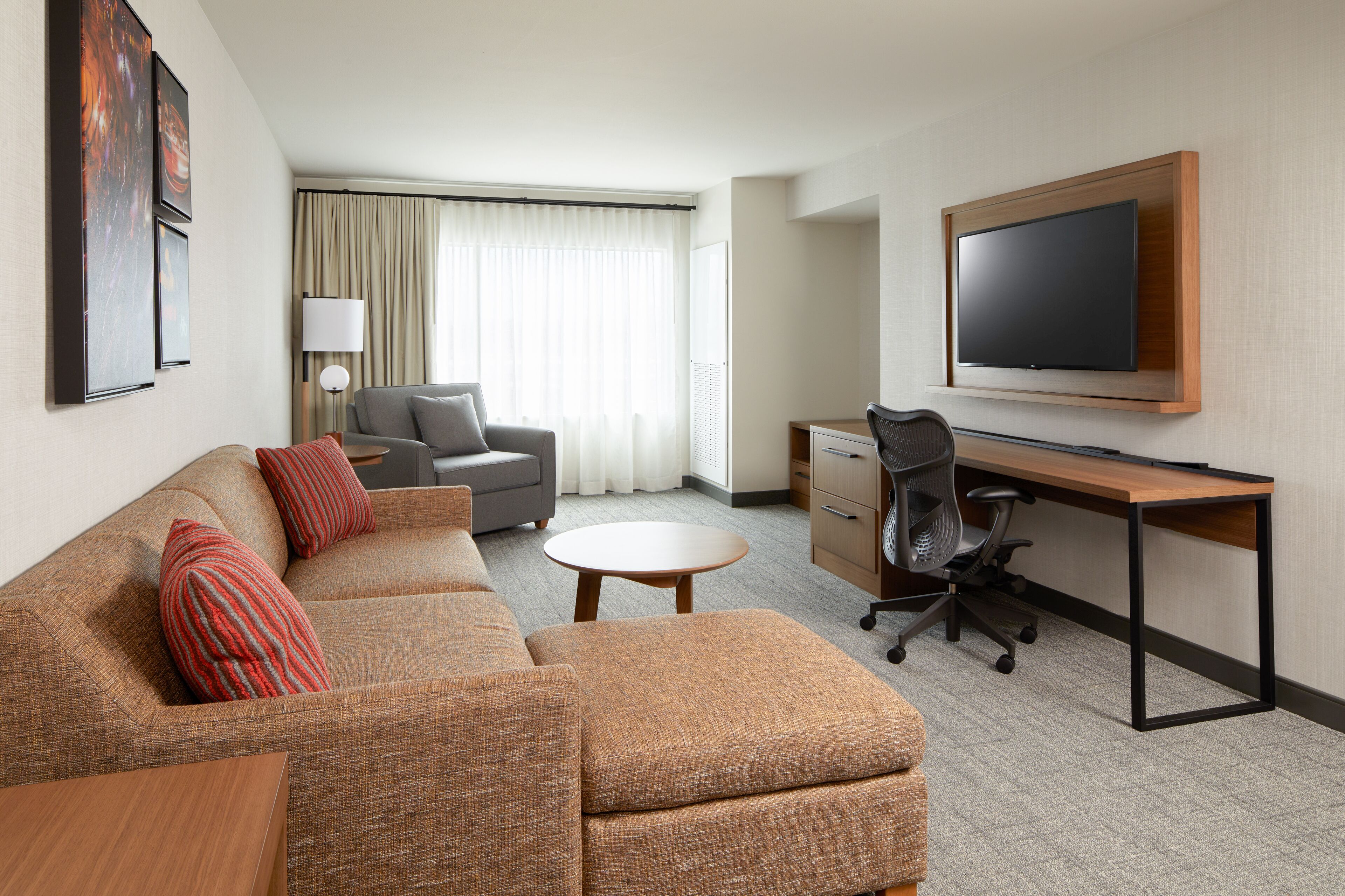 Une chambre d’hôtel équipée d’un canapé, d’un bureau, d’une télévision et d’une lampe.