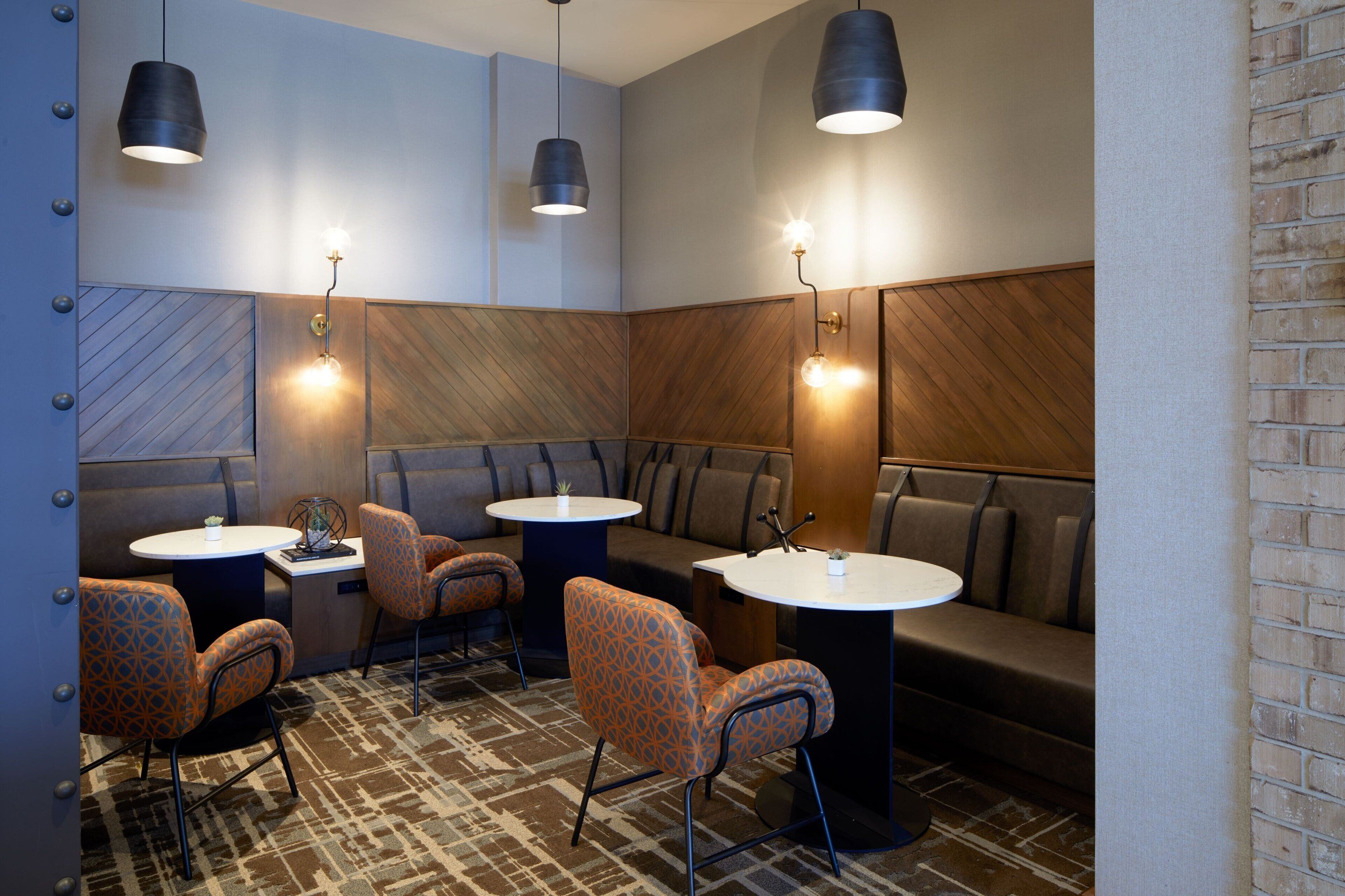 Un espace de détente moderne, doté de sièges et de tables, avec un sol à motifs et des éléments décoratifs en bois.