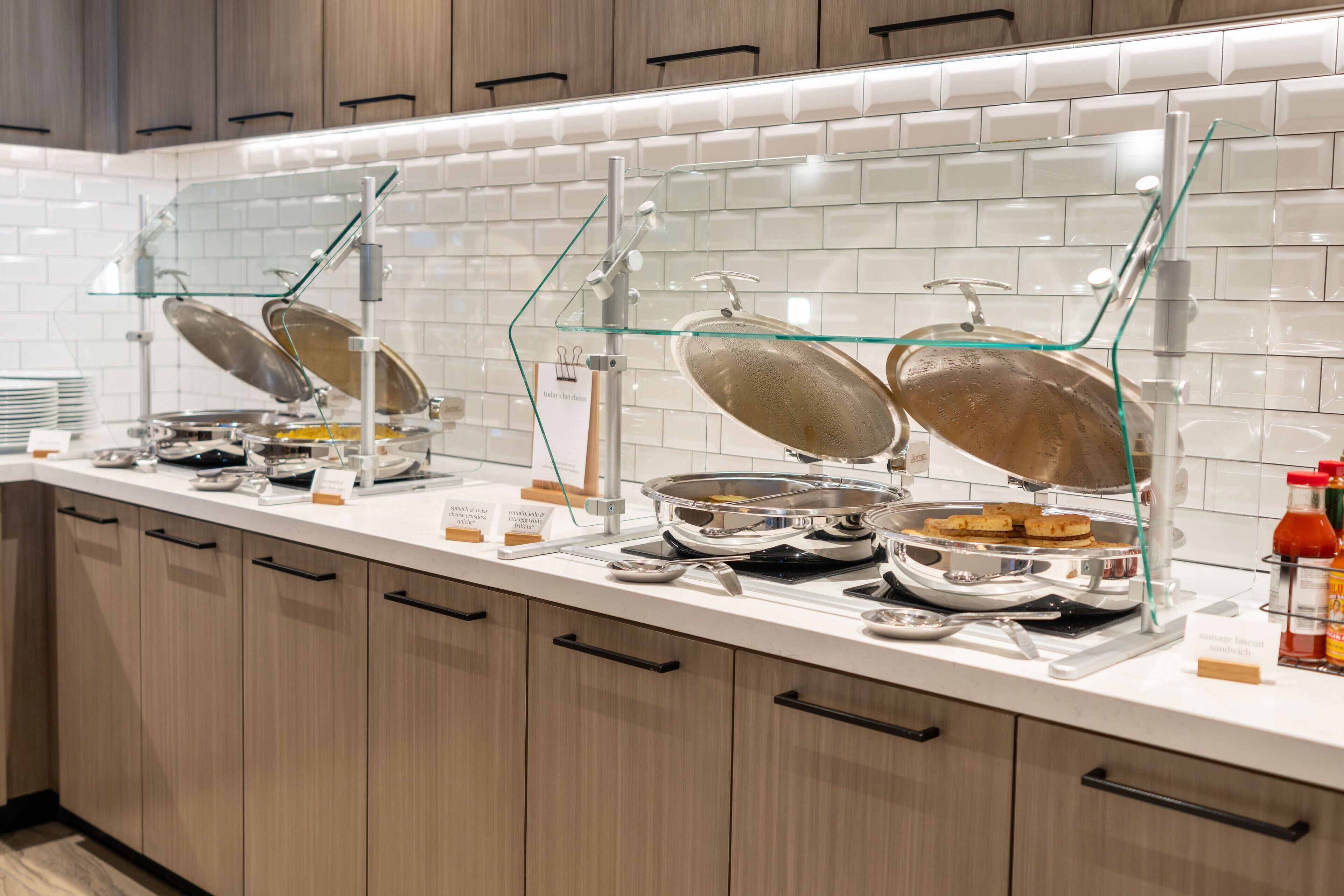 A buffet setup with multiple self-service stations, including hot and cold food options, and condiment dispensers.