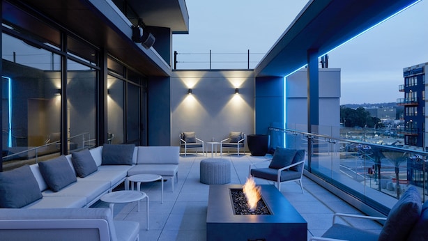 A modern outdoor lounge area with a fire feature, seating, and large windows offering city views. - Residence Inn by Marriott San Francisco Airport Millbrae Station (Millbrae)