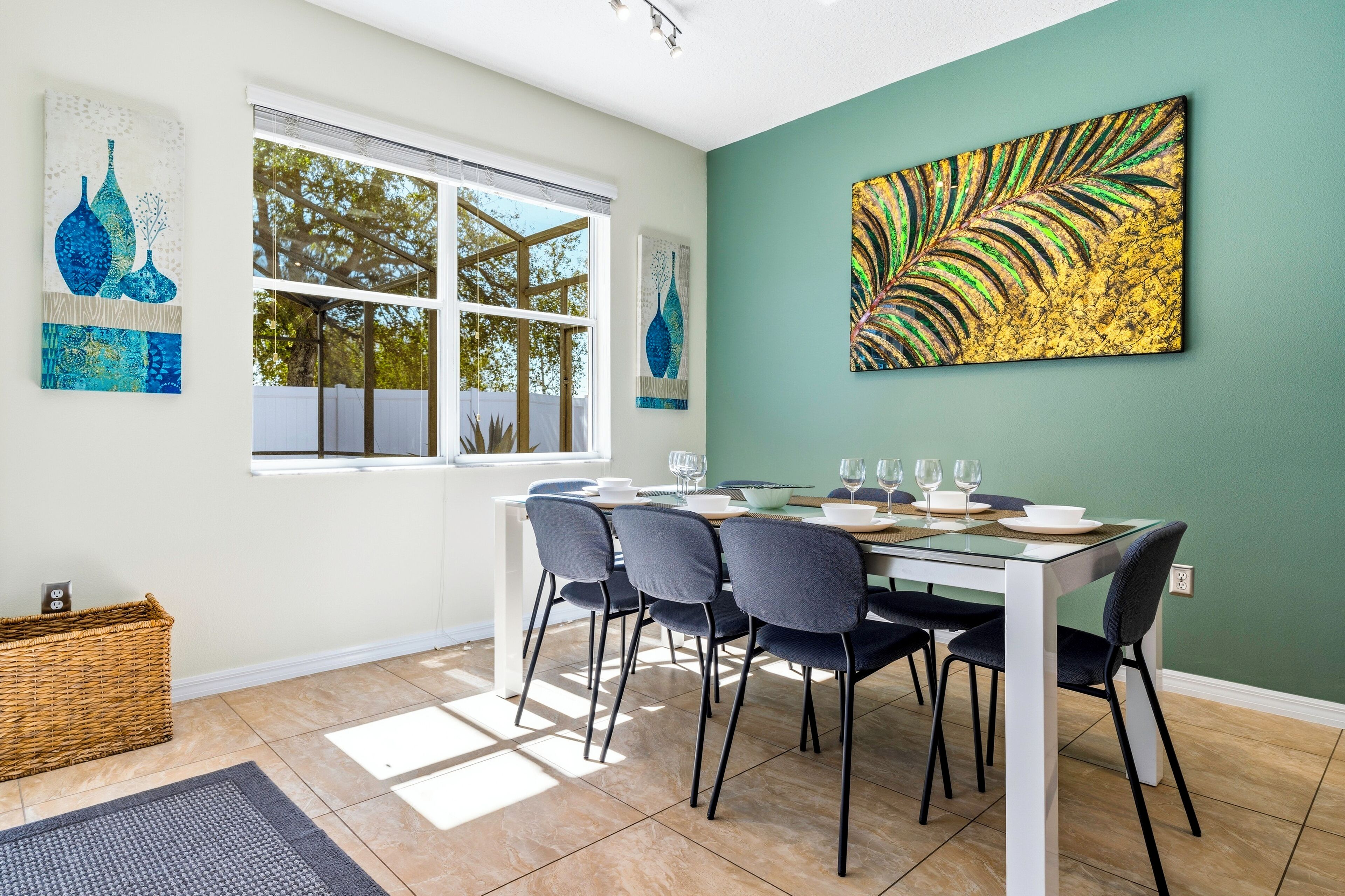 A dining area with a white table, dark chairs, and a large window.