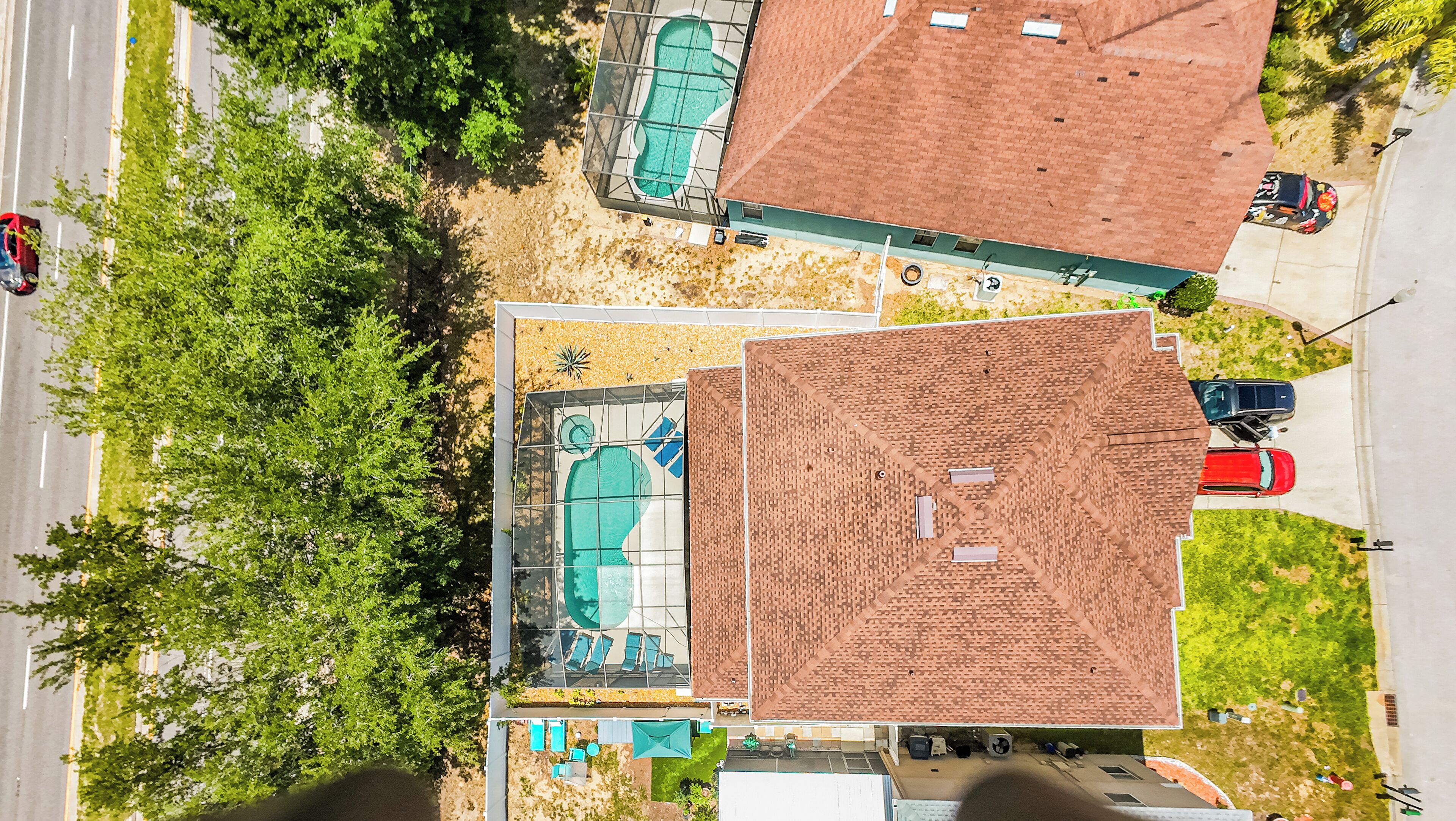 Zona residencial con piscina, un edificio de techo rojo y un automóvil estacionado.