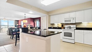 A modern kitchen with white cabinets, a black countertop, and a central island. - Yacht Club Villas #2-405 Extraordinary and Spacious Condo! (North Myrtle Beach)