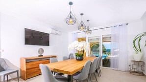 A modern dining area with a wooden table, grey chairs, and pendant lighting.