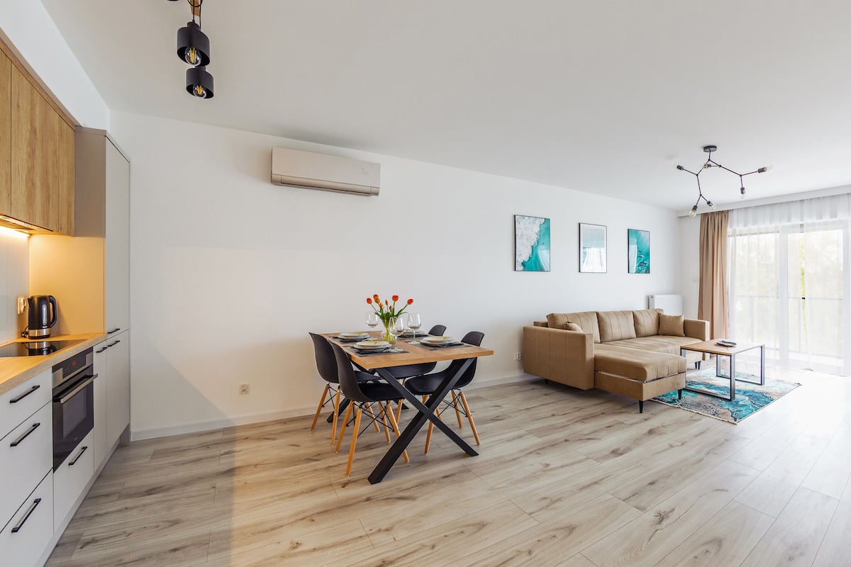 A modern apartment with a dining area, a sofa, and a kitchen.