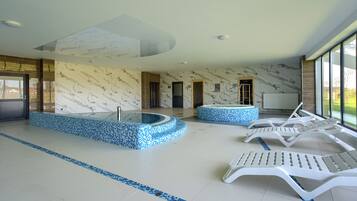 Relax by the pool surrounded by a blue mosaic tile border and lounge chairs.
