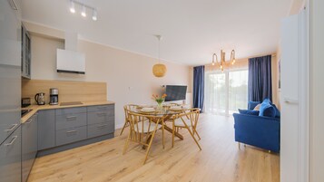 Una cocina moderna con armarios grises, una mesa de comedor de madera y un sofá azul en la sala de estar.