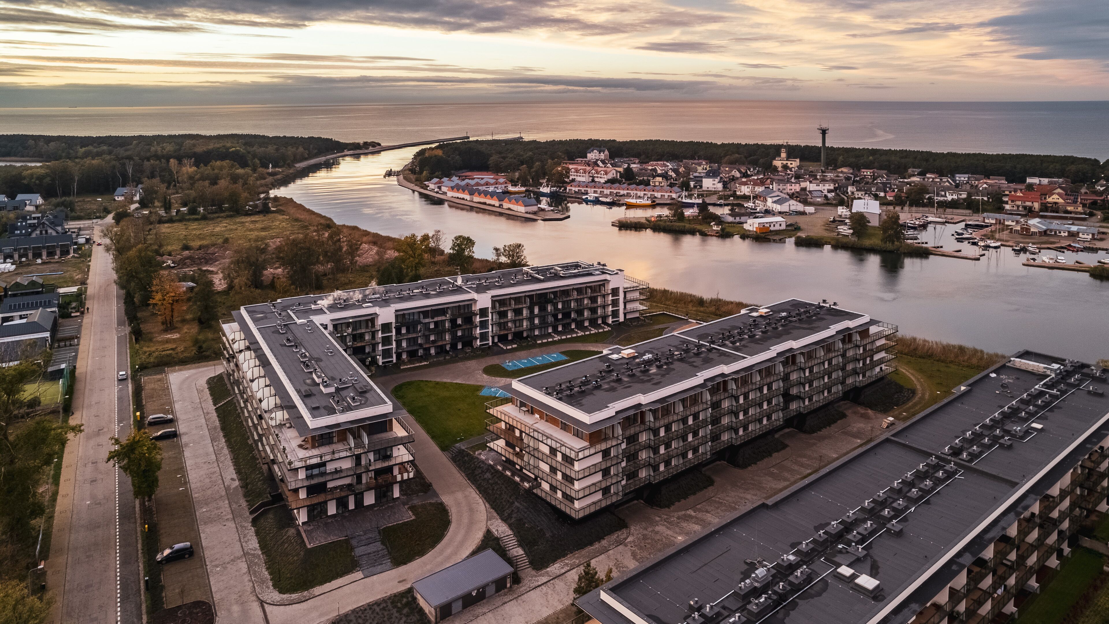 A modern multi-story hotel with a parking lot and a view of a river and town.