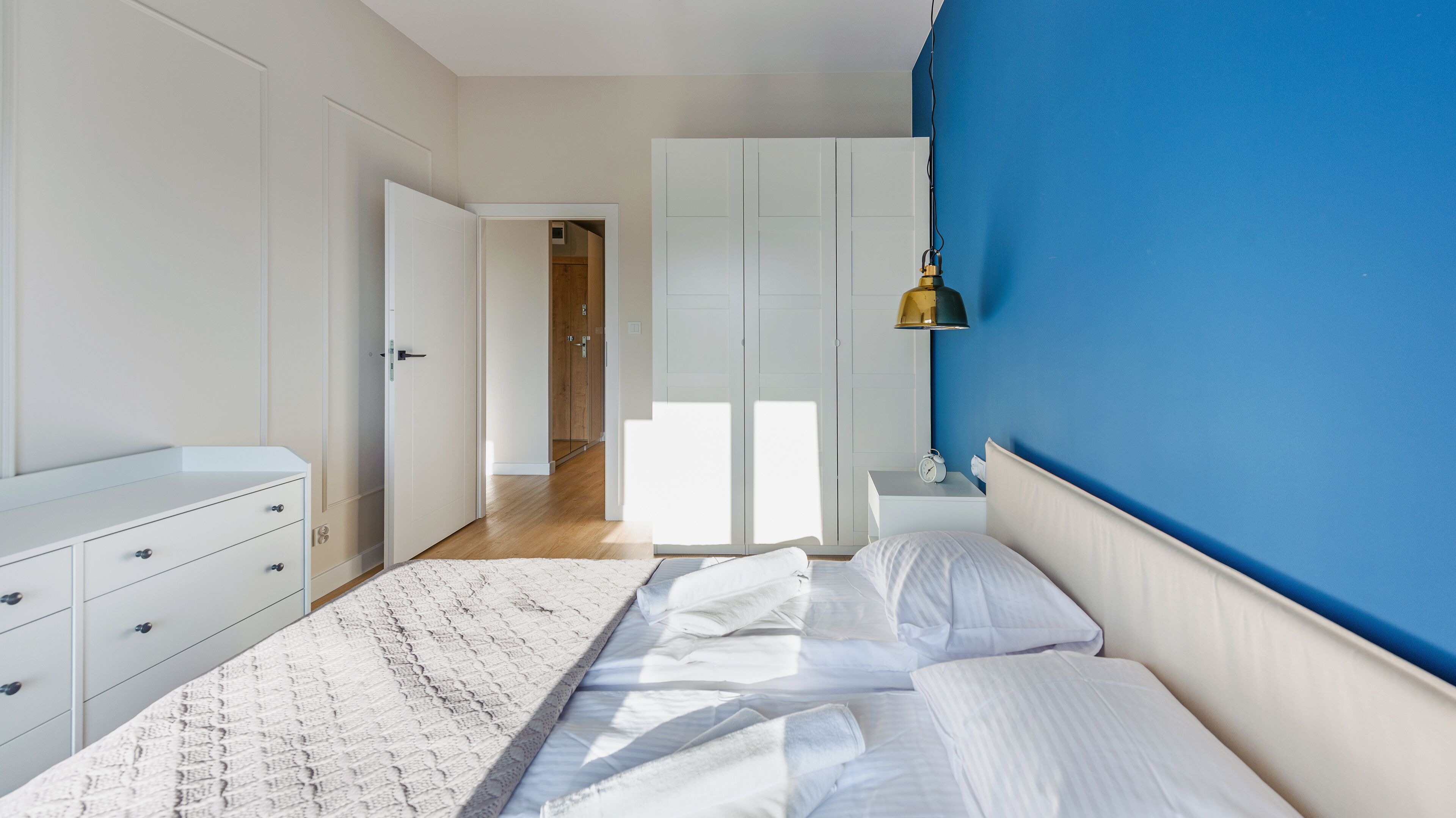 A bedroom with a bed, a nightstand, a dresser, and a wardrobe.