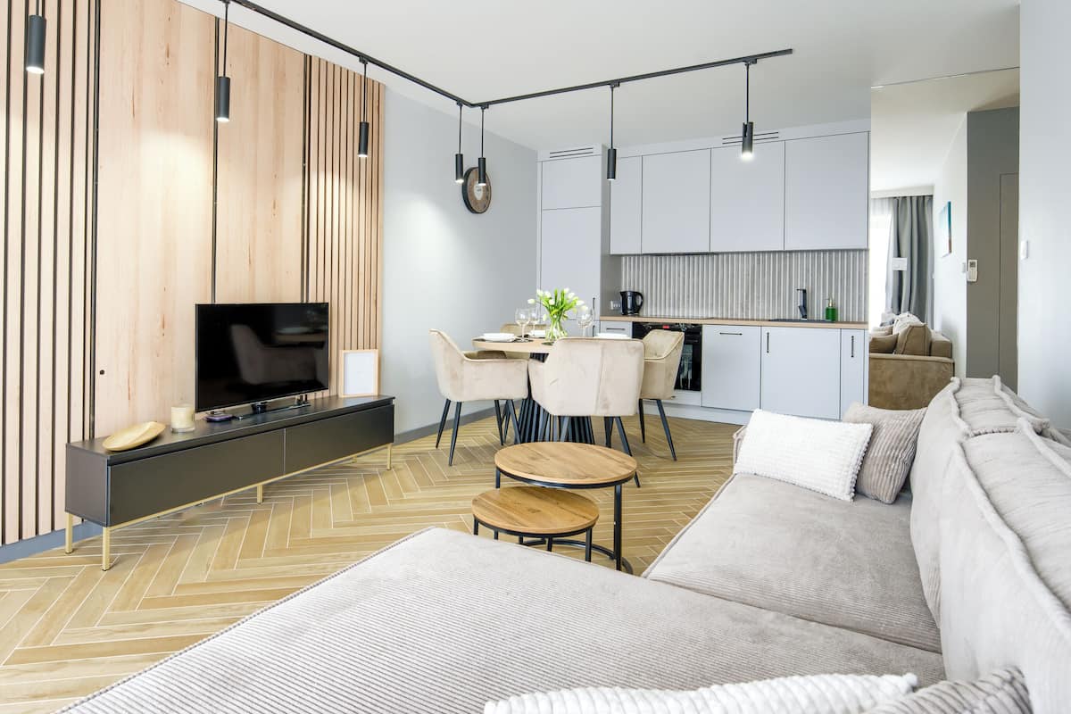 A modern living room with a sofa, TV, and dining area.