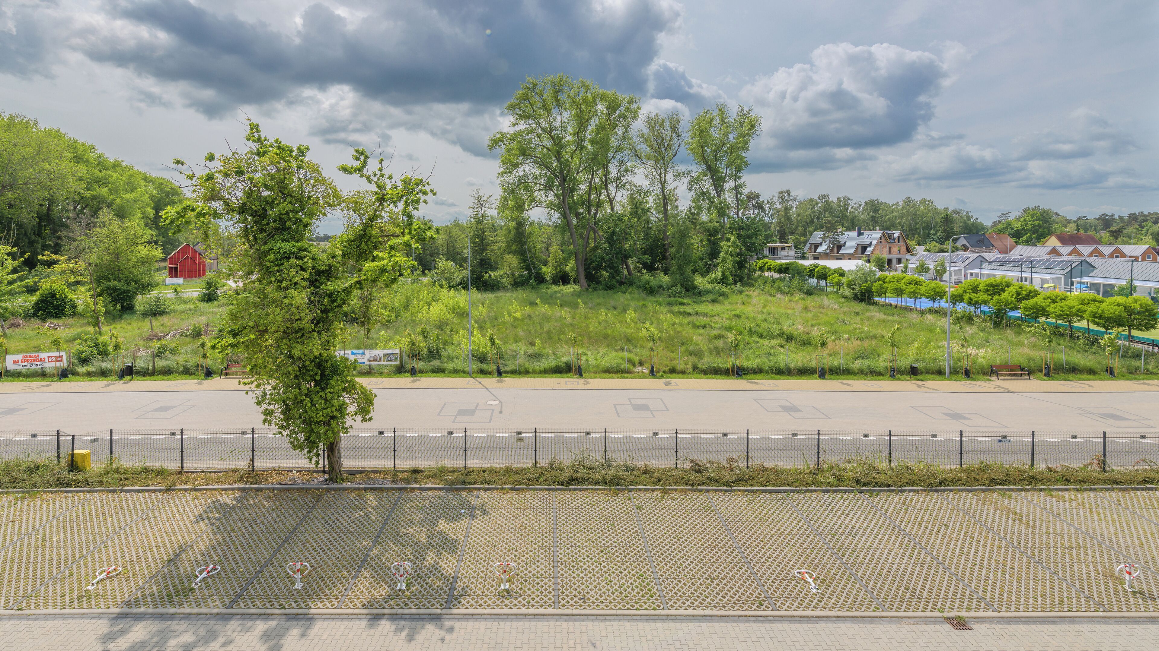 A parking lot with a fence and trees in the background.