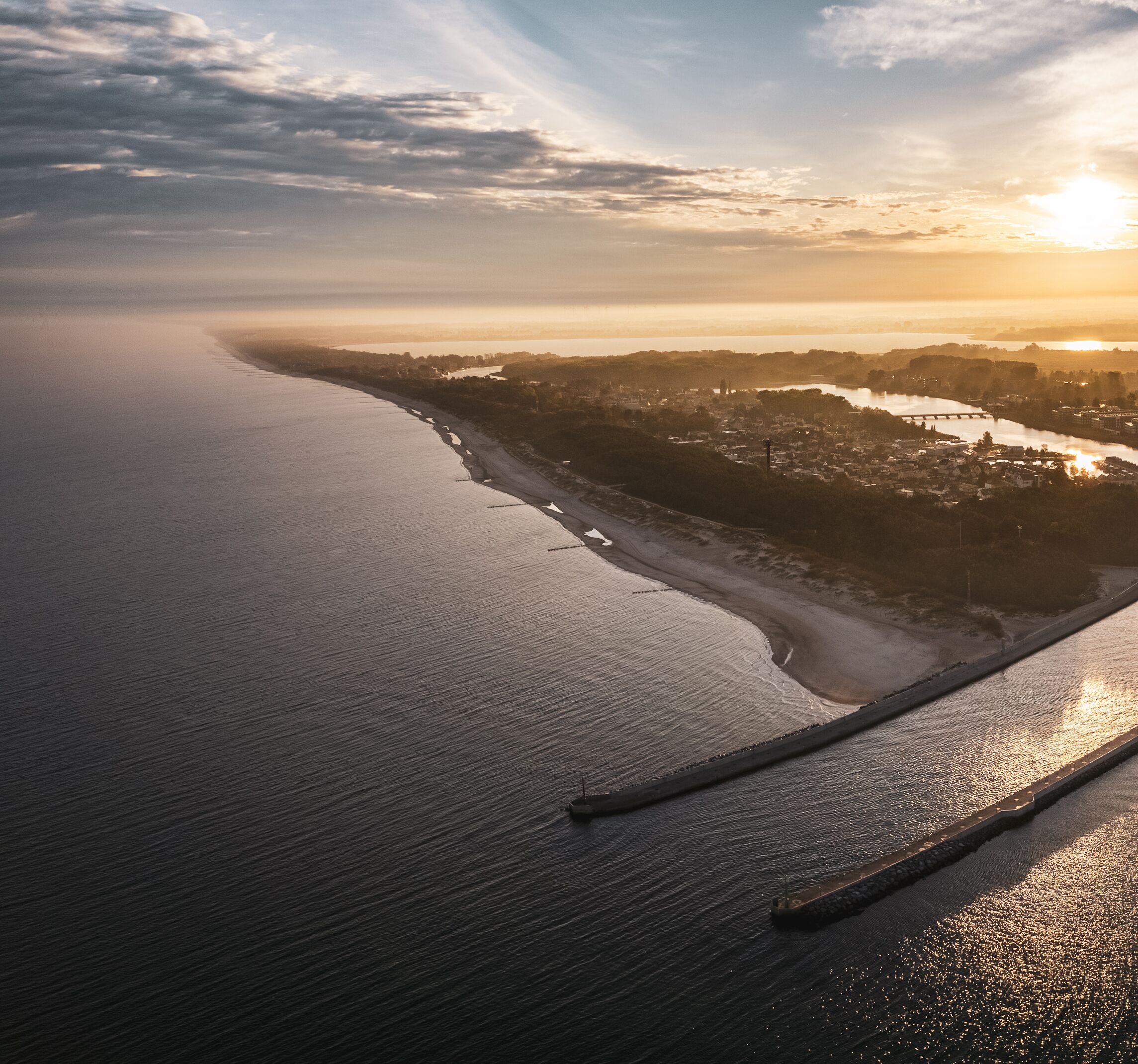 An aerial view of a coastal area with a beach, a river, and a bridge.