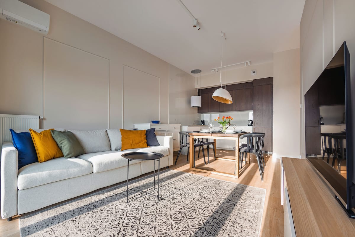 A modern living room with a sofa, coffee table, and dining area.