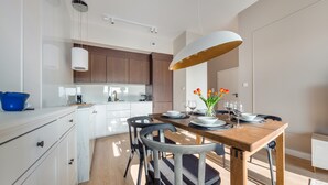 Una cocina moderna con armarios blancos, una mesa de comedor de madera dispuesta con platos, vasos y un jarrón de tulipanes.