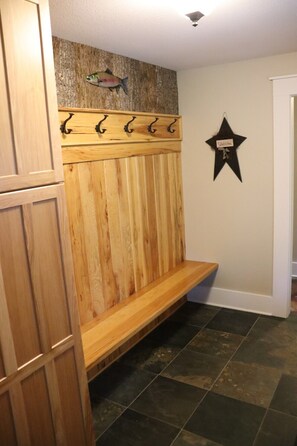 A wooden bench with hooks, a welcome sign, and a star decoration in a room with tiled flooring.