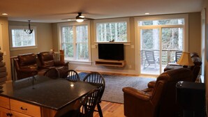 A spacious living room with a fireplace, large windows, and a dining area.