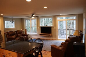 A spacious living room with a fireplace, large windows, and a dining area. - Private, River, Hot tub, Fire table, fishing (Marion)