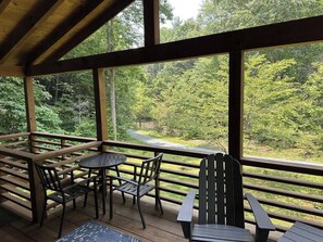 Une terrasse en bois avec une table et des chaises, donnant sur une zone boisée.