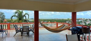 Un balcon avec un hamac, des chaises et un barbecue.