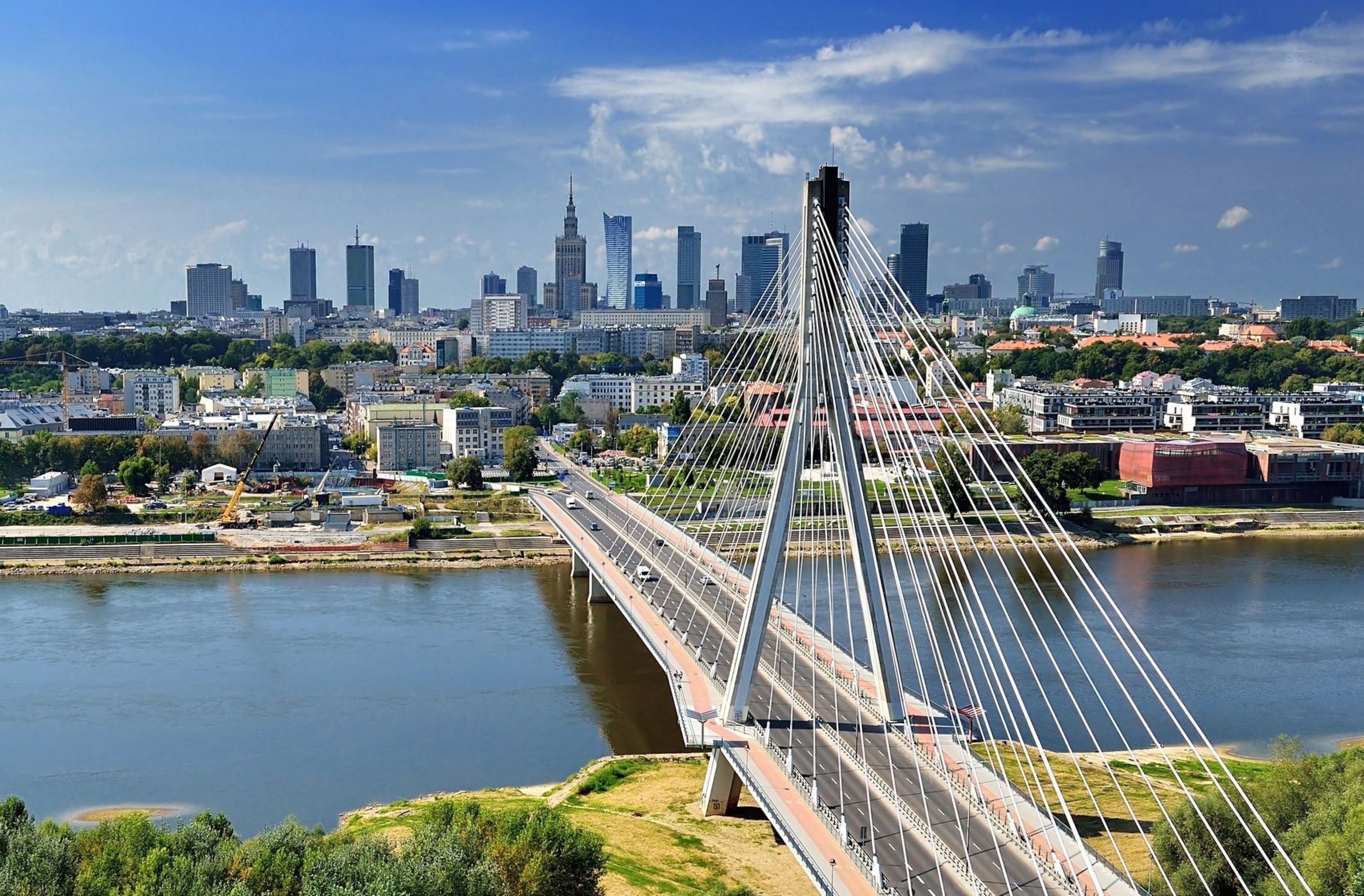 A modern cable-stayed bridge with a clear view of the city skyline in the background.