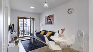 A modern living room with a sofa, dining table, and chairs. There is a window, a door, and a clock on the wall. - Lumina cozy apartament in Warsaw (Warsaw)