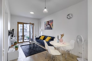 A modern living room with a sofa, dining table, and chairs. There is a window, a door, and a clock on the wall. - Lumina cozy apartament in Warsaw (Warsaw)