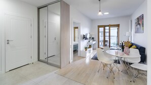 A modern, well-lit living area with a dining table, chairs, and a sofa. - Lumina cozy apartament in Warsaw (Warsaw)