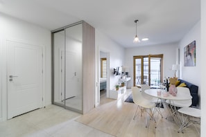 A modern, well-lit living area with a dining table, chairs, and a sofa. - Lumina cozy apartament in Warsaw (Warsaw)