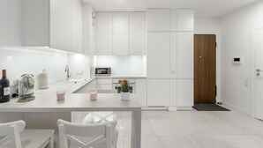 A modern kitchen with white cabinetry, a dining table with chairs, a microwave, and a wooden door. - Lumina cozy apartament in Warsaw (Warsaw)