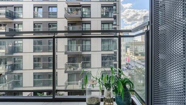 A modern apartment with large windows, a balcony, and potted plants. - Lumina cozy apartament in Warsaw (Warsaw)