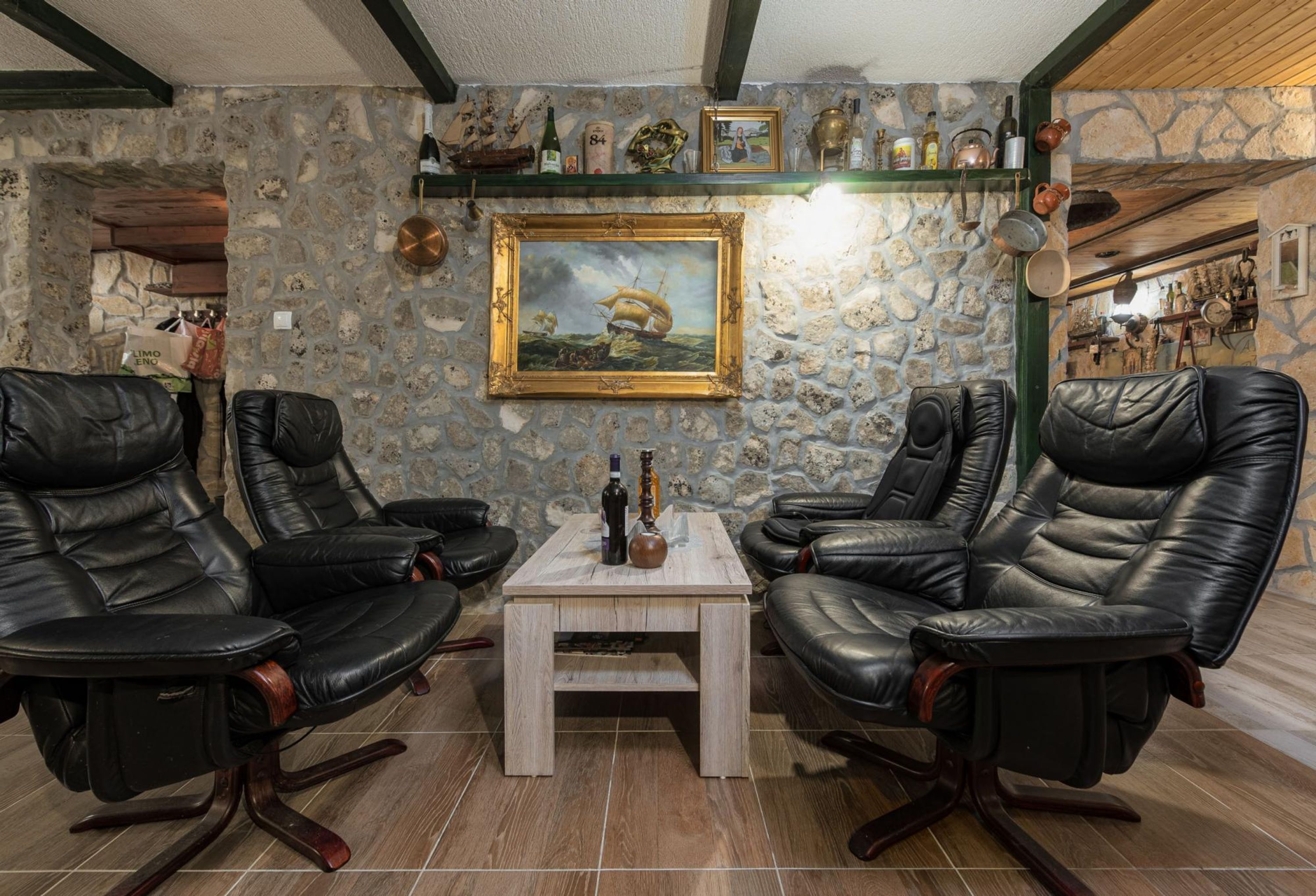A room with stone walls, a wooden ceiling, and leather chairs around a small table.