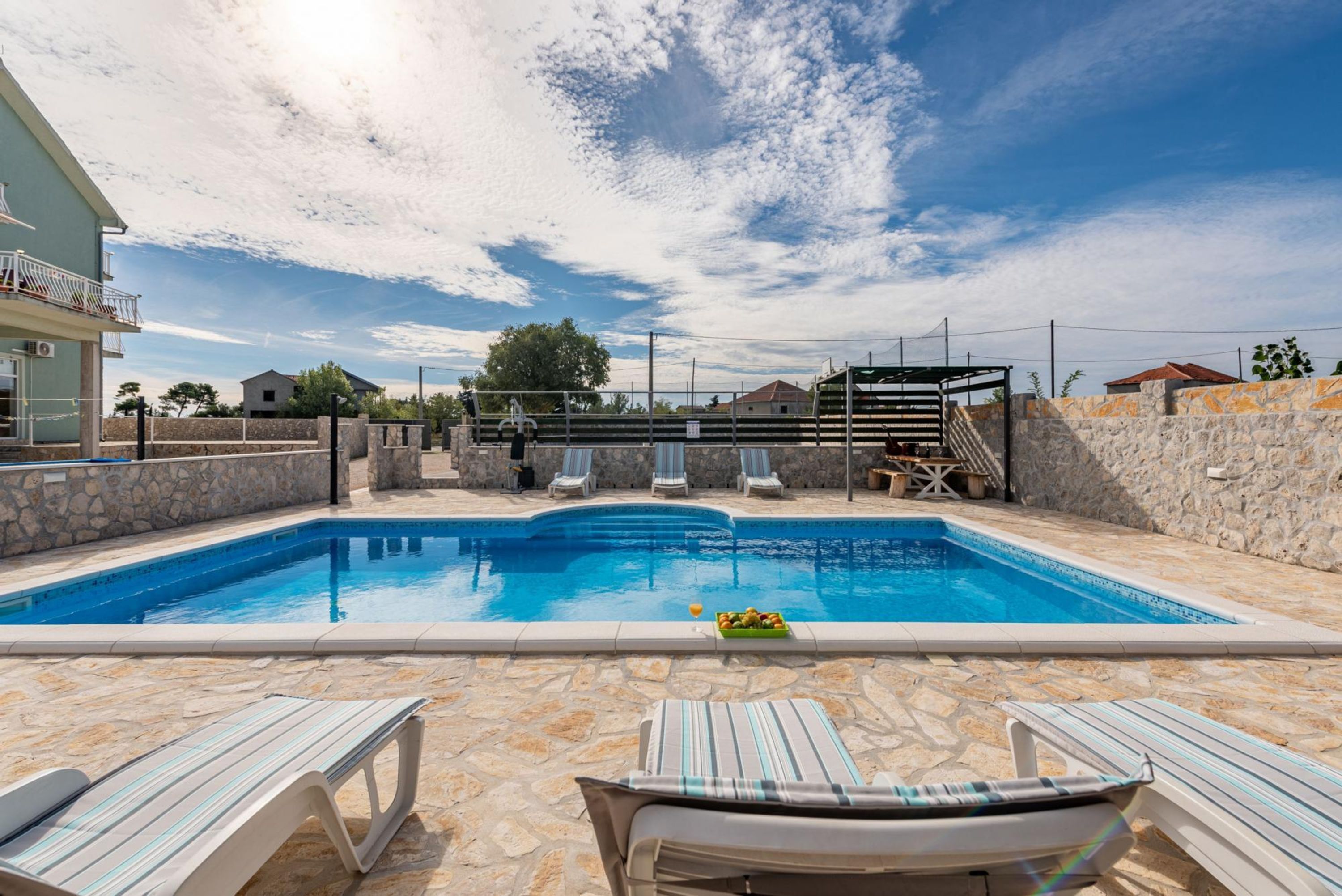Una piscina con lettini e una parete in pietra.
